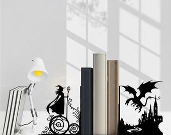 May include: A black metal bookend set featuring a silhouette of a witch holding a staff on one side and a flying dragon above a castle on the other. The two pieces support a row of three books, with the text CRAFTNAMESIGN visible at the bottom.