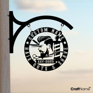 Puede incluir: Señal de metal negro con un diseño de barbero y el texto "CUSTOM NAME HAIR CUTS & SHAVE EST-2025".