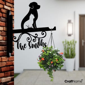 May include: Black metal silhouette of a dog and cat with a hanging planter and the text "The Smiths" on a black metal sign.
