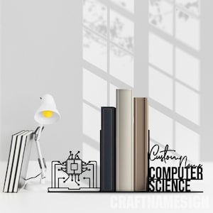 May include: A black metal bookend set featuring a computer chip circuit board design on one side and the text "Custom Name COMPUTER SCIENCE" on the other, supporting three books between them next to a white desk lamp.