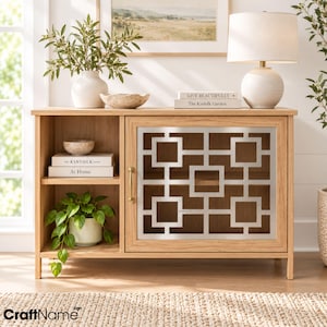 Può includere: Un mobile in legno di rovere chiaro con uno scaffale aperto a sinistra e un'anta singola a destra. L'anta presenta un rivestimento in metallo argentato con un motivo geometrico quadrato e una maniglia verticale. Il mobile ha quattro gambe.