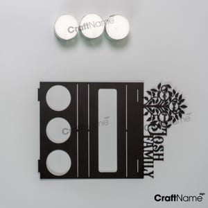 Puede incluir: Un letrero familiar de madera negra con el texto "JOSH FAMILY" y un dise&ntilde;o de &aacute;rbol. Tres velas de t&eacute; blancas est&aacute;n encima del letrero. El letrero tiene tres recortes circulares y un recorte rectangular.