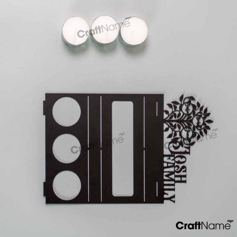 Puede incluir: Un letrero familiar de madera negra con el texto "JOSH FAMILY" y un dise&ntilde;o de &aacute;rbol. Tres velas de t&eacute; blancas est&aacute;n encima del letrero. El letrero tiene tres recortes circulares y un recorte rectangular.