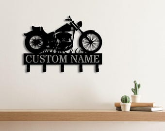 Könnte beinhalten: Ein schwarzer Wand-Schlüsselhalter aus Metall mit der Silhouette eines Motorrads über einer rechteckigen Platte mit dem Text CUSTOM NAME und fünf nach unten gerichteten Haken zum Aufhängen von Gegenständen.