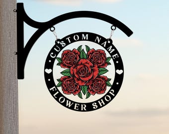 May include: Black metal sign with a floral design. The sign reads "CUSTOM NAME FLOWER SHOP" with a heart on each side of the text. The floral design features red roses with green leaves.
