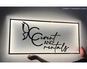 May include: A white illuminated sign with a black border and a black butterfly design. The text on the sign reads "Event and Rentals".