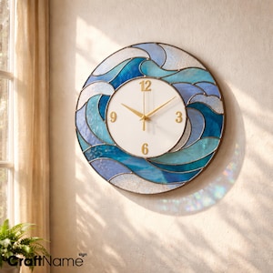 May include: Circular wall clock featuring a wave design. The clock face is white with gold hands and numerals. The wave design incorporates shades of blue and white. The clock is mounted on a beige wall.