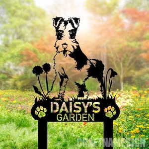May include: Black metal garden sign featuring a silhouette of a wirehaired terrier dog, two dandelions, and the text "Daisy's Garden" with paw prints on either side.