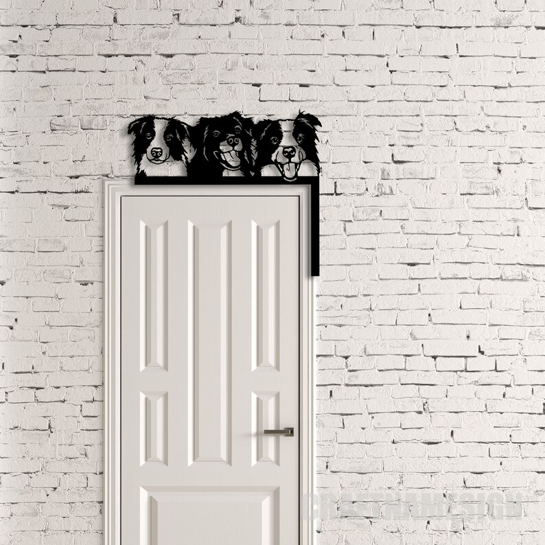 K&ouml;nnte beinhalten: Ein schwarzer Metall-T&uuml;rtopper mit drei Border-Collie-Hunde-K&ouml;pfen, die &uuml;ber die Oberseite schauen. Der T&uuml;rtopper ist &uuml;ber einer wei&szlig;en T&uuml;r mit einer wei&szlig;en Backsteinwand dahinter montiert.