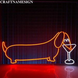 May include: Neon sign featuring a dachshund dog with a martini glass. The dog and glass are outlined in bright orange and white neon against a dark background. The sign has the text "CRAFTNAMESIGN" at the top.
