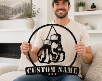 Könnte beinhalten: Ein schwarzes Metall-Wandschild mit einem kreisförmigen Rahmen und einem ausgeschnittenen Design von zwei hängenden Boxhandschuhen in der Mitte. Unter dem Kreis zeigt ein rechteckiges Banner den Text CUSTOM NAME in fetten Großbuchstaben mit drei Sternen.