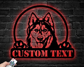 May include: A circular wall sign featuring a black silhouette of a husky dog head with paws resting on a rectangular base. The sign is illuminated by a vibrant red LED light and includes the text CUSTOM TEXT on the base, controlled by a remote.