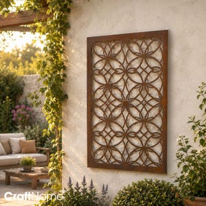May include: A rectangular metal wall panel featuring a rust-colored finish and an intricate, repeating geometric pattern of interlocking circles. The panel is mounted vertically on a textured wall, showcasing a symmetrical lattice design.