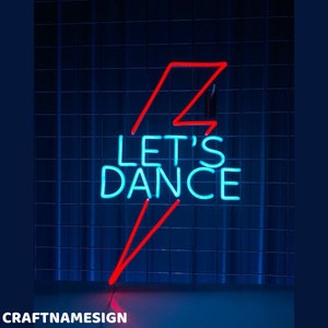 Op de afbeelding: Een neonbord met een rood bliksemontwerp en de woorden "Let's Dance" in blauw neon.