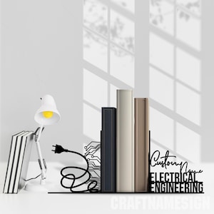 Puede incluir: Sujeta libros de metal negro con un diseño de placa de circuito y el texto "Custom Name ELECTRICAL ENGINEERING" sobre una superficie blanca. Los sujetalibros sostienen una pila de libros.