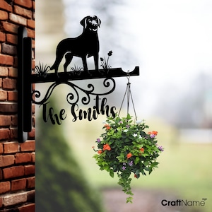 Könnte beinhalten: Schwarze Metall-Silhouette eines Hundes mit dem Text "The Smiths" auf einem Hängepflanztopf mit Blumenarrangement.