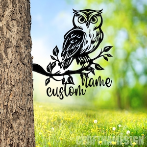 May include: Black metal silhouette of an owl perched on a branch with leaves. The words "custom name" are written below the owl.