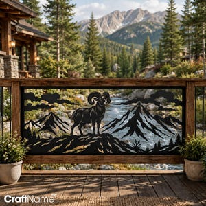May include: A black metal decorative railing panel featuring a cutout silhouette of a bighorn sheep standing on a rocky mountain ridge, with jagged mountain peaks, pine trees, and clouds in the background, framed by a wooden deck railing.