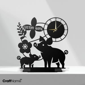 May include: Black metal pig-themed clock with a pig and piglet silhouette, floral accents, and a clock face. The clock has the text "CUSTOM NAME" and "CraftName" on the base.