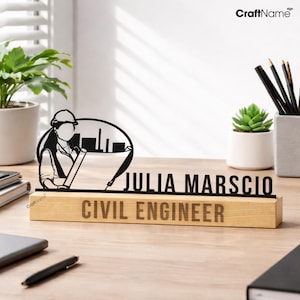 Może przedstawiać: Czarna metalowa tabliczka na biurko z sylwetką inżyniera w kasku trzymającego plan budowy, z wygrawerowanym napisem JULIA MARSCIO oraz CIVIL ENGINEER na prostokątnej podstawie z jasnego drewna.
