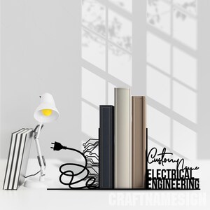 May include: A black metal bookend featuring a graphic of an electrical plug and circuit board pattern, with the text "Custom Name" and "ELECTRICAL ENGINEERING" displayed in a bold, sans-serif font, supporting three books next to a desk lamp.