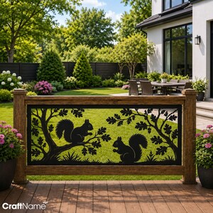 May include: A black metal decorative railing insert featuring a laser-cut silhouette of two squirrels perched on tree branches with oak leaves and acorns. The rectangular panel is framed by a brown wood-textured railing on a wooden deck.
