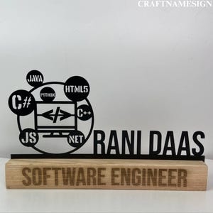 May include: Black metal plaque with a computer monitor and various programming languages like Java, C#, Python, HTML5, C++, JavaScript, and .NET. The plaque reads "Rani Daas Software Engineer" and is mounted on a wooden base.