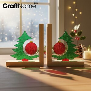 May include: Wooden Christmas tree bookends with a green tree design and a red ornament. The bookends are on a wooden base and are set against a window with a snowy background. The CraftName sign is visible.
