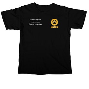 Puede incluir: Camiseta negra con una huella de pata y el texto "Unleashing love, paw by paw, forever cherished." y "MADDIE" debajo de la huella de pata.