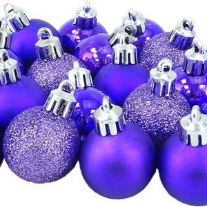 Puede incluir: Un conjunto de adornos navideños morados con tapas plateadas. Algunos adornos tienen un acabado brillante y liso, mientras que otros están cubiertos de purpurina. Estas bolas decorativas son perfectas para la decoración navideña.