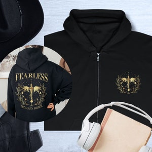 Può includere: Felpa con cappuccio nera con zip, con un design di drago dorato sul davanti e le parole "Fearless Dragon Rider" sul retro.