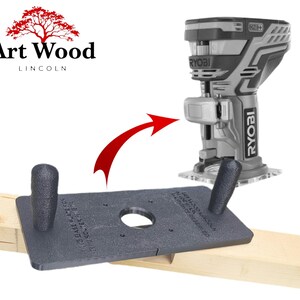 May include: A black base plate for a Ryobi router with two black handles, attached to a wooden surface. A red arrow points to a Ryobi router. The Art Wood Lincoln logo is in the upper left corner.