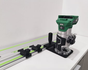 以下が含まれることがあります： 緑と黒の電気ルーターが、緑色のラインが入った銀色のトラックに取り付けられています。ルーターは黒いベースと透明なプラスチック製のガードが付いています。トラックには黒いノブと「festool」という文字が印刷されています。