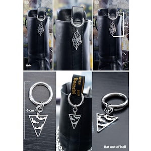 K&ouml;nnte beinhalten: Silberfarbene Schuhanh&auml;nger mit Gothic-Thema. Ein Anh&auml;nger zeigt ein Spinnennetz-Design, w&auml;hrend ein anderer eine dreieckige Form mit Fledermaus-Silhouetten hat. Die Anh&auml;nger sind an einem Ring befestigt und messen 5,5 cm und 6 cm in der L&auml;nge.