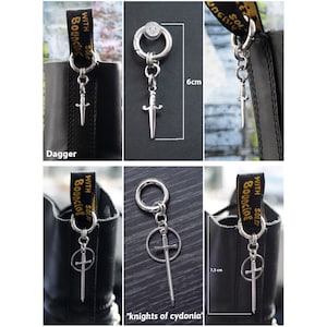 K&ouml;nnte beinhalten: Silberne Stiefelanh&auml;nger mit Dolch- und Schwertanh&auml;ngern. Ein Dolch-Anh&auml;nger ist 6 cm lang. Ein anderer Anh&auml;nger hat ein Schwert in einem Kreis und ist 7,5 cm lang. Die Anh&auml;nger sind an schwarzen Stiefeln befestigt.