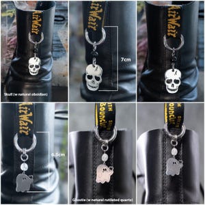K&ouml;nnte beinhalten: Silberne Schuhanh&auml;nger mit Totenkopf- und Geisteranh&auml;ngern, die an Metallringen h&auml;ngen. Der Totenkopf-Anh&auml;nger hat nat&uuml;rliche Obsidianperlen, der Geisteranh&auml;nger hat nat&uuml;rliche Rutilquarzperlen. Die Stiefel sind ca. 7 cm und 6,5 cm hoch.
