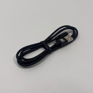 May include: Black USB charging cable with a USB-A connector and a USB-C connector. The cable is braided and has a black plastic band to keep it coiled. The USB-A connector has the text "SRC" printed on it.