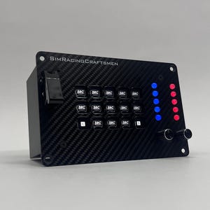 May include: A black control panel with a carbon fiber texture, featuring multiple buttons labeled "SRC", toggle switches, and indicator lights. The text "SIMRACING CRAFTSMEN" is printed on the top.