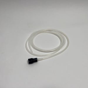 Puede incluir: Un tubo de plástico flexible, transparente y hueco enrollado en forma circular. Un extremo del tubo está fijado a una pieza conectora cilíndrica de color negro sólido, mientras que el otro extremo del tubo permanece abierto y sin fijar.