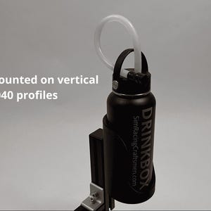 May include: A black Drinkbox bottle with a white tube attached to the cap, held in a black holder mounted on a vertical 4040 profile. The text "Can be mounted on vertical 4040 profiles" is visible on the left side of the image.