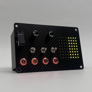 May include: Black control panel with a carbon fiber texture. It features a toggle switch, two rotary dials, three toggle switches, and four illuminated red push buttons. A grid of yellow LEDs is on the right.
