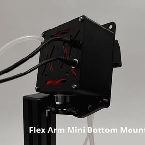 May include: A black electronic device with a carbon fiber texture and red accents, featuring two black cables and a clear tube connected to the top. The unit is attached to a black vertical stand and includes the text Flex Arm Mini Bottom Mount.