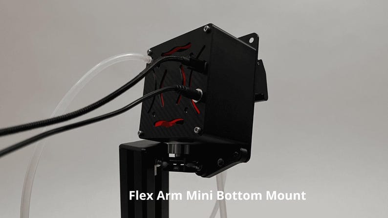 May include: A black electronic device with a carbon fiber texture and red accents, featuring two black cables and a clear tube connected to the top. The unit is attached to a black vertical stand and includes the text Flex Arm Mini Bottom Mount.