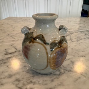May include: A grey ceramic vase with two handles and a brown, green and purple abstract design.