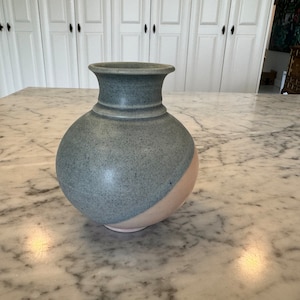 Könnte beinhalten: Eine Keramikvase mit hellblauer und rosafarbener Glasur. Die Vase hat einen runden Körper und einen schmalen Hals.