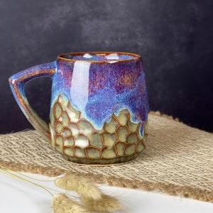 The photo shows a handmade cup with a square handle with a volume of 350 ml. It is textured and brown on the bottom, smooth and iridescent on top. This is our bestseller.