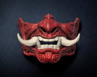 May include: A red and white Oni mask with a fierce expression. The mask has sharp teeth and horns, and is decorated with intricate details.