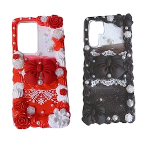 May include: Two phone cases with a decorative design. One case is red and white with a red bow and the other is black and white with a black bow. Both cases have white lace and pearl accents.