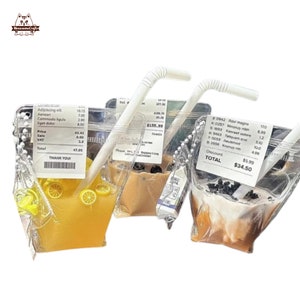 May include: Three clear plastic bags with zipper closures, each containing a different beverage. The bags are hanging from silver chains. The first bag contains a yellow liquid with lemon slices. The second bag contains a brown liquid with black tapioca pearls. The third bag contains a white liquid with black tapioca pearls. Each bag has a receipt attached with a total price. The first receipt shows a total of £47.95. The second receipt shows a total of £155.99. The third receipt shows a total of £34.50.