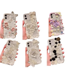 May include: Six different phone cases with various 3D embellishments. The cases are white and feature different designs, including flowers, butterflies, and other decorative elements.